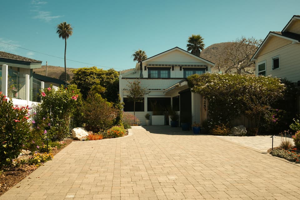 A two-story house at the end of a long paver driveway
